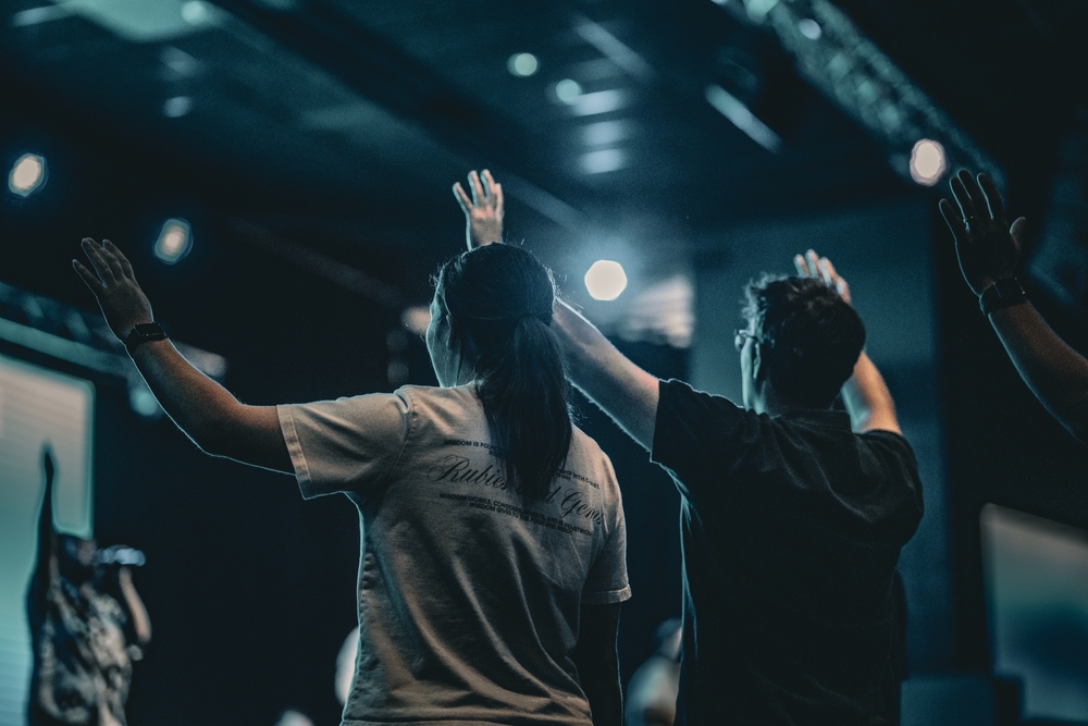 Two people raise their hands in worship at a church service, reflecting Christian counseling in Edmond and Oklahoma City.
